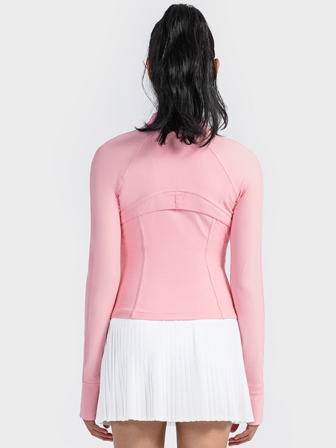 Back view of Millennia Carnation Pink Zip-Up Long Sleeve Sports Jacket paired with a white pleated skirt. Perfect for workouts!