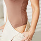 Woman wearing Everyday Full Size Basic Tank Bodysuit in brown with a beige skirt, showcasing the sleek and stretchy fit.