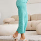 Woman wearing turquoise RFM Jeans, Tummy Control High Waist Raw Hem, stylish and modern fit, paired with white heeled sandals.