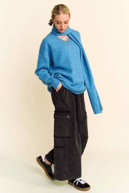 Stylish model in blue V-neck dropped shoulder sweater with scarf, paired with black wide-leg pants and sneakers.