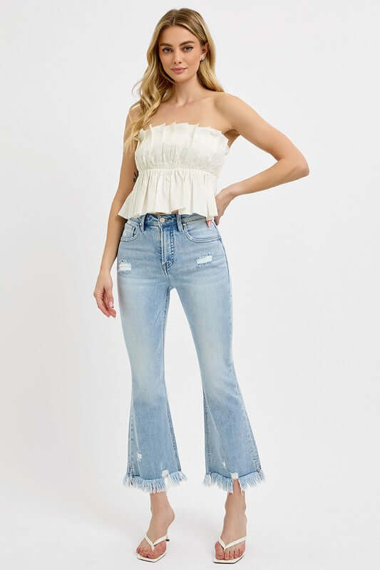 Model showcasing RISEN full size raw hem distressed cropped flare jeans with a stylish white top and trendy sandals.