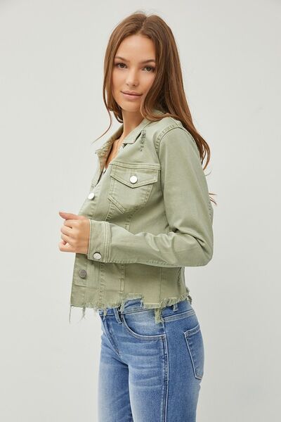 Stylish woman wearing a cropped green raw hem button-up denim jacket with jeans, showcasing trendy fashion vibes.