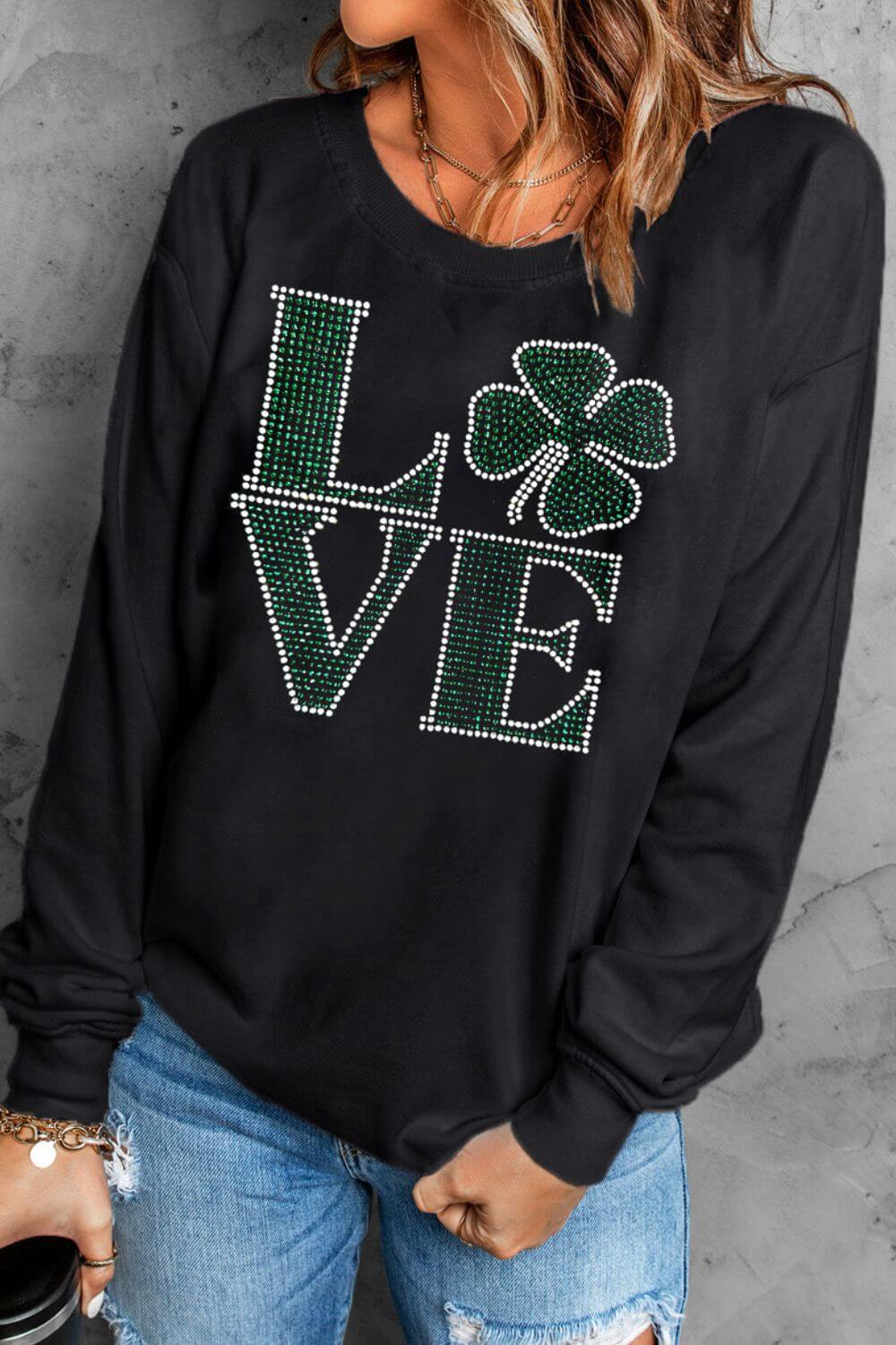 Black sweatshirt featuring rhinestone "LOVE" design with clover, perfect for style and comfort. Ideal for playful wardrobes.