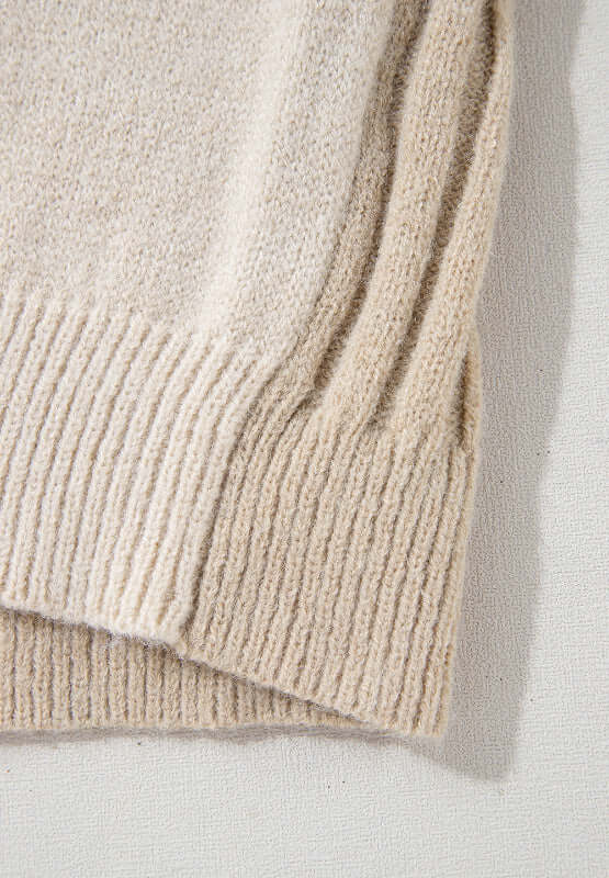 Close-up of tan cable-knit fabric from Bella Road color block sweater, showcasing texture and ribbed hem. Cozy and stylish design.