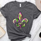 Bella Road Mardi Gras graphic T-shirt featuring vibrant purple and green fleur-de-lis design on a gray background.