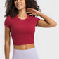 Millennia cropped sports t-shirt in red worn by a smiling woman, perfect for yoga and fitness activities.