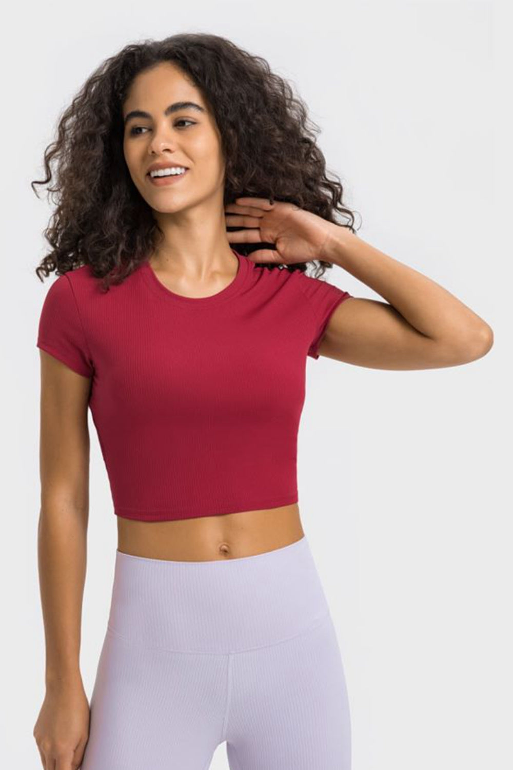 Millennia cropped sports t-shirt in red worn by a smiling woman, perfect for yoga and fitness activities.