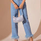 Stylish model wearing Bella Road high rise straight jeans with plush hem, paired with a silver purse and heels.