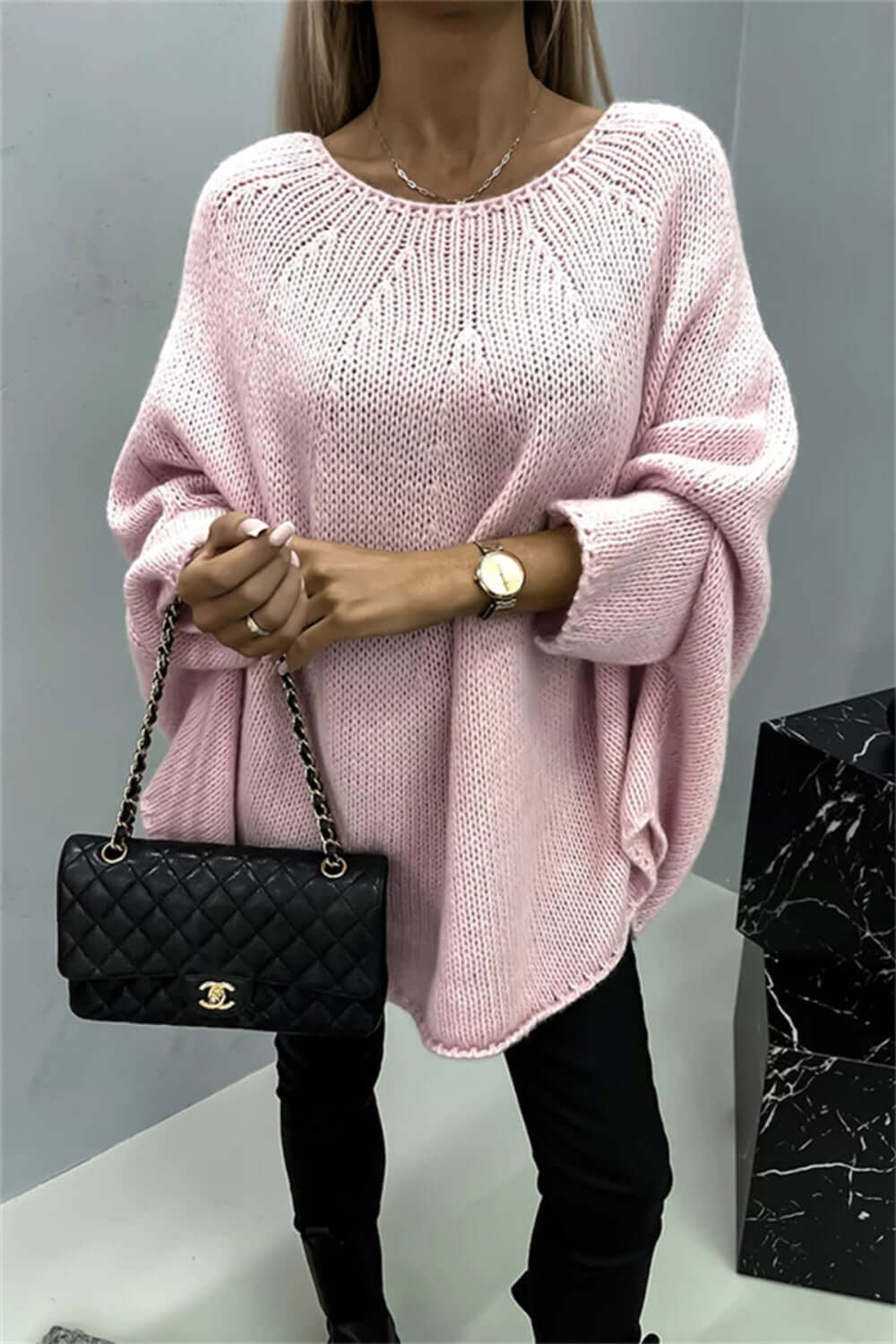 Stylish pink batwing sleeve sweater with round neck paired with black quilted handbag, perfect for a cozy, fashionable look.