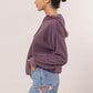 Woman wearing a cozy purple brushed hoodie with kangaroo pocket and denim shorts, showcasing casual style.