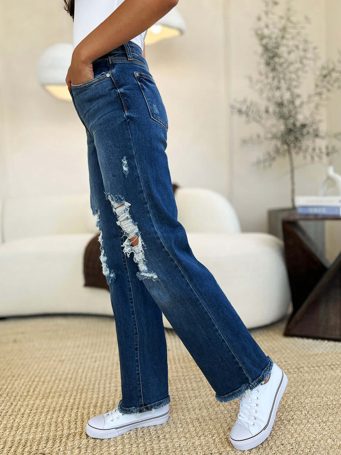 Woman wearing full size mid rise distressed raw hem Judy Blue Jeans with white sneakers.