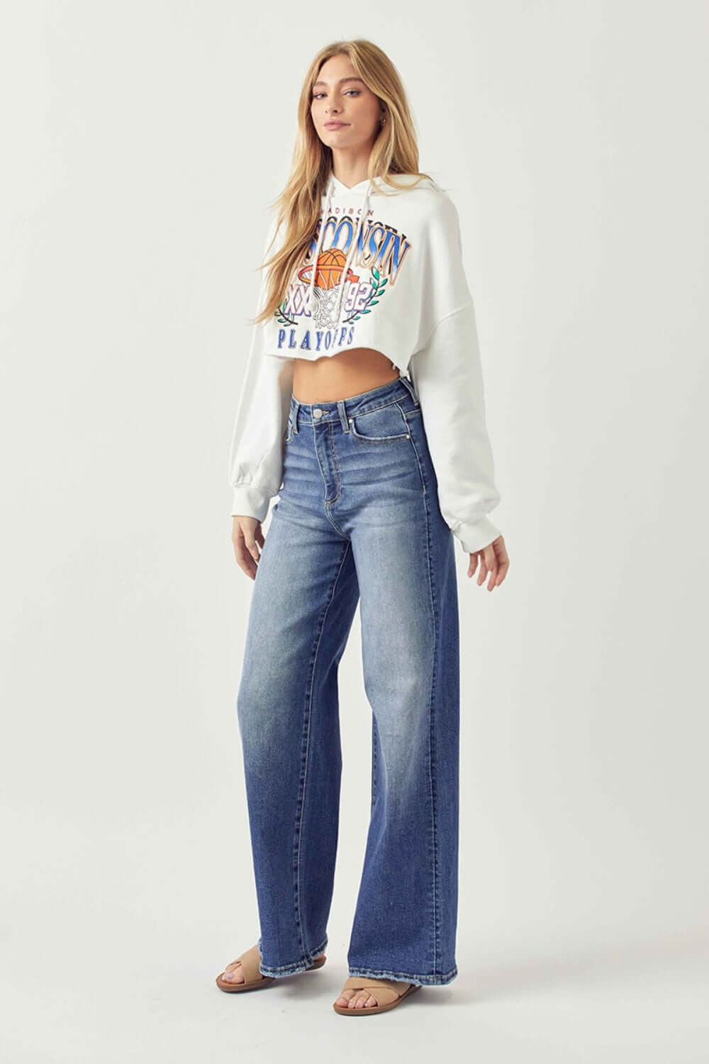 Woman wearing high rise, wide leg Risen Jeans paired with a white cropped sweatshirt, showcasing a stylish and comfortable fashion look.