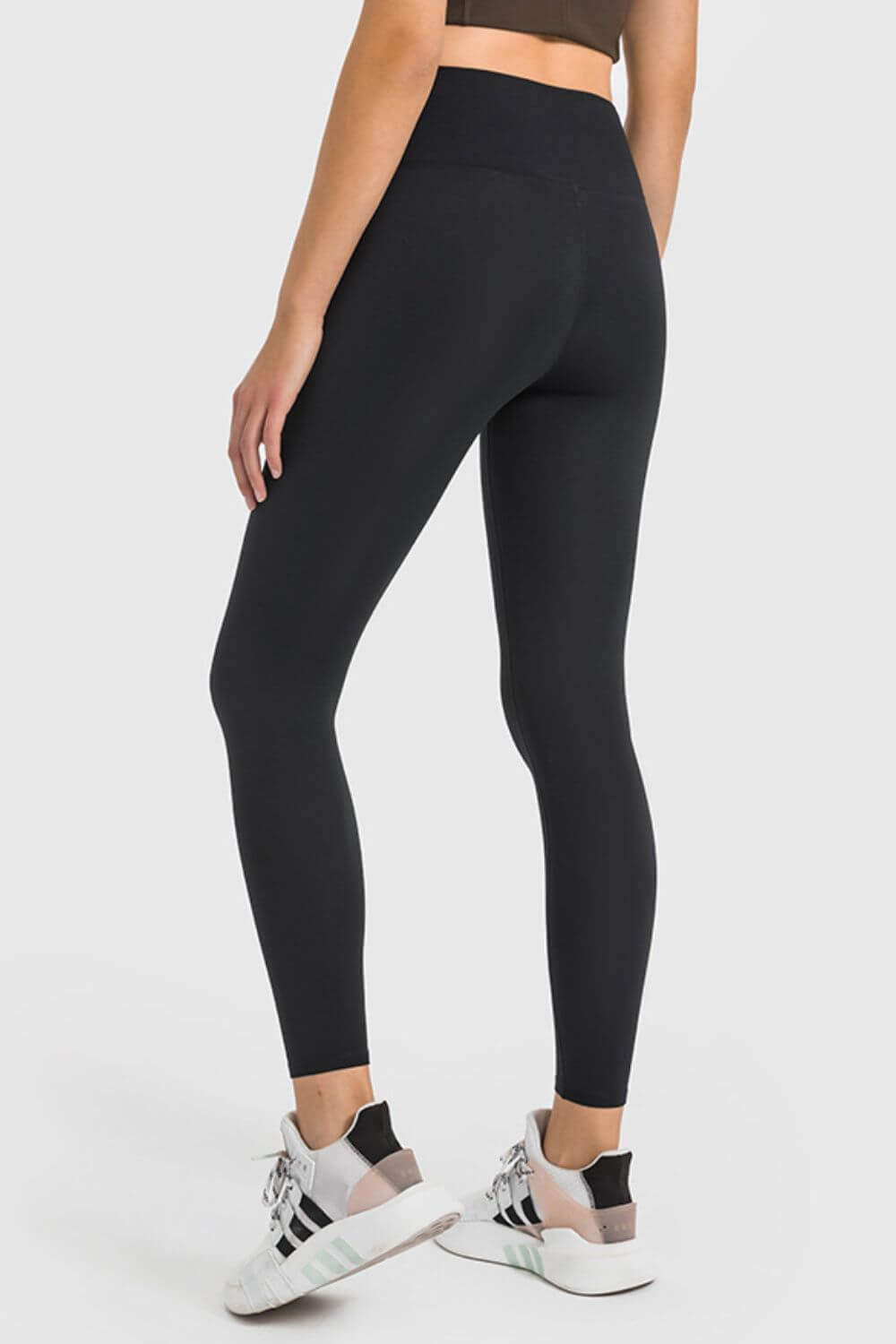 Woman wearing black high waist ankle-length yoga leggings, showcasing comfort and style for workouts.