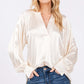 Woman wearing a notched long sleeve blouse in viscose with raglan sleeves and split neckline, paired with jeans, perfect for versatile styling.