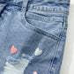 Bella Road Mini Denim Skirt with heart details, distressed design, and raw hem for a cute and edgy look.