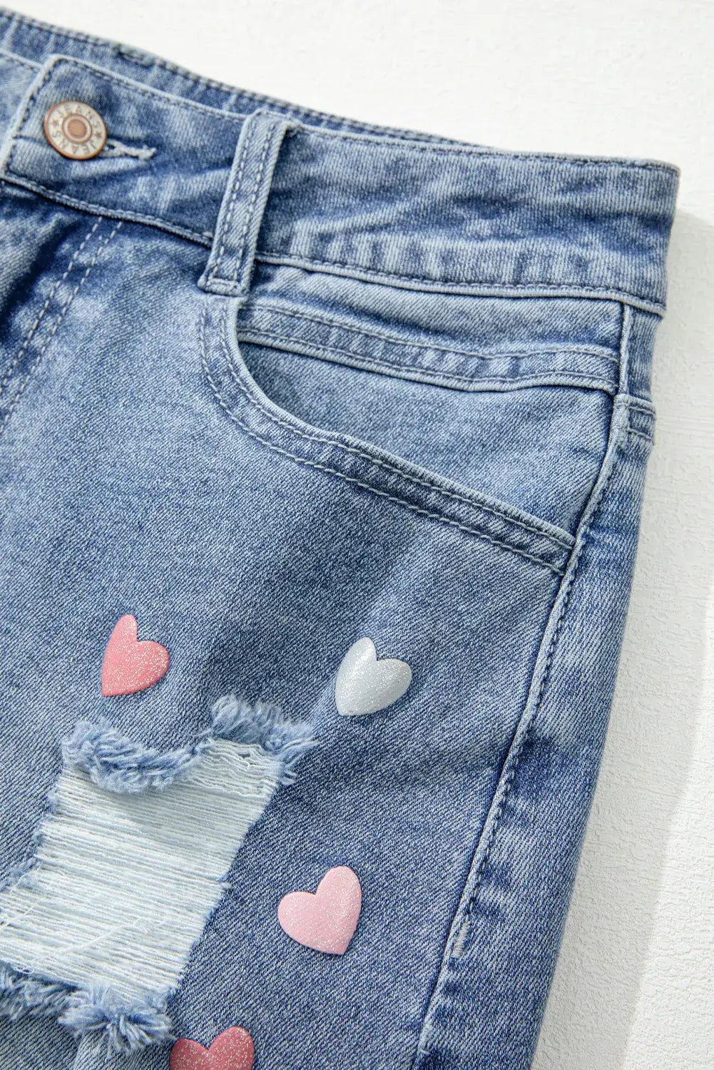 Bella Road Mini Denim Skirt with heart details, distressed design, and raw hem for a cute and edgy look.