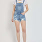 Person wearing Risen Jeans distressed raw hem denim overalls, showcasing trendy and edgy casual style.