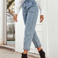 Woman in Bella Road Tied Straight Leg Jeans, showcasing stylish pockets and a trendy tie waist, paired with chic heels.