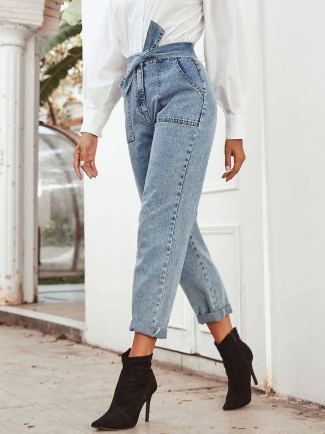 Woman in Bella Road Tied Straight Leg Jeans, showcasing stylish pockets and a trendy tie waist, paired with chic heels.