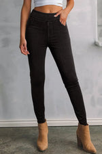 Petite woman wearing black skinny jeans with pockets and tan boots, showing sleek and flattering fit.