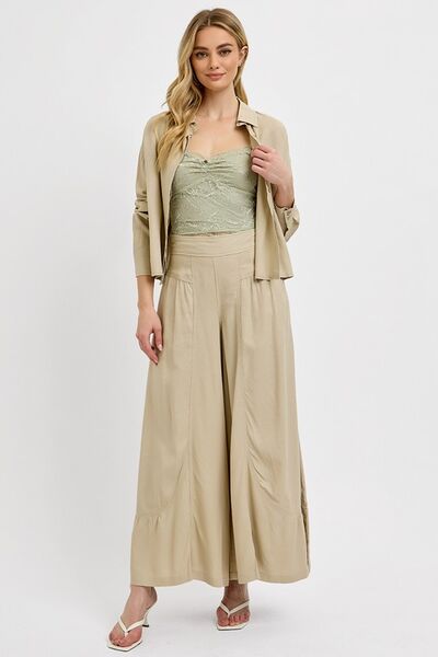 Stylish woman in beige outfit featuring a flowy top and wide-leg pants, perfect for casual or formal occasions.