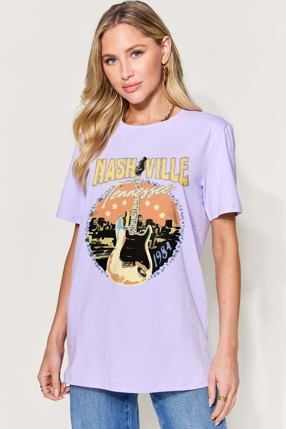 Woman wearing a lavender graphic round neck short sleeve T-shirt with "Nashville, Tennessee" design.