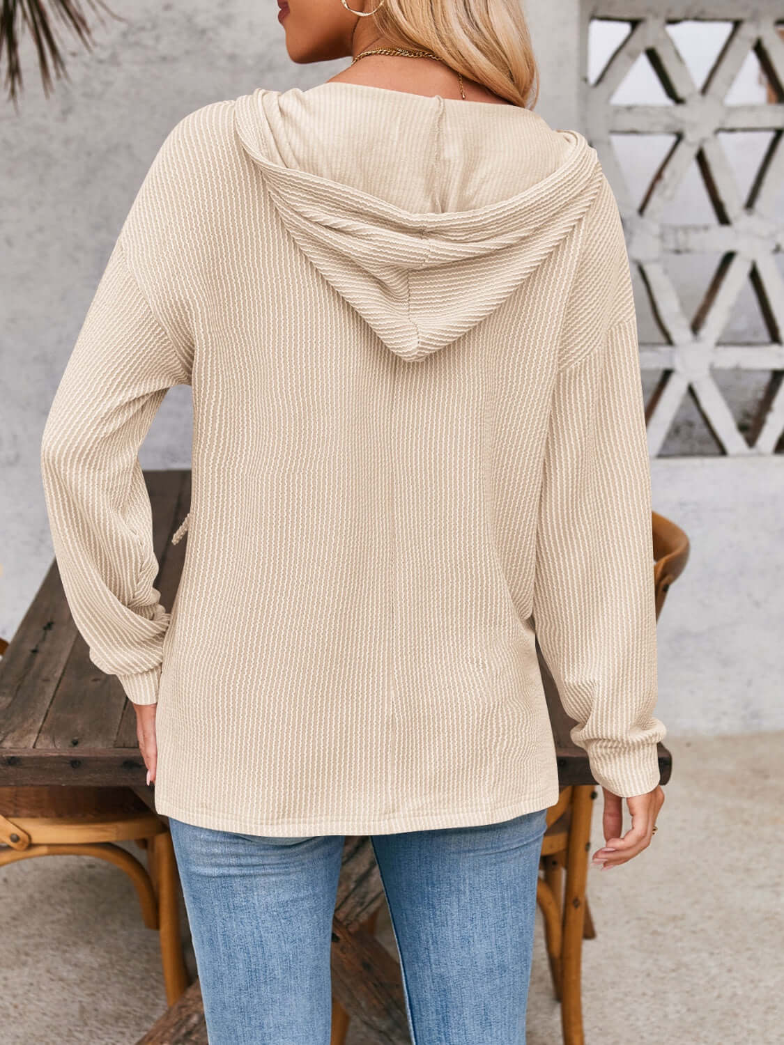 Woman wearing beige drawstring dropped shoulder long sleeve hoodie with back view.