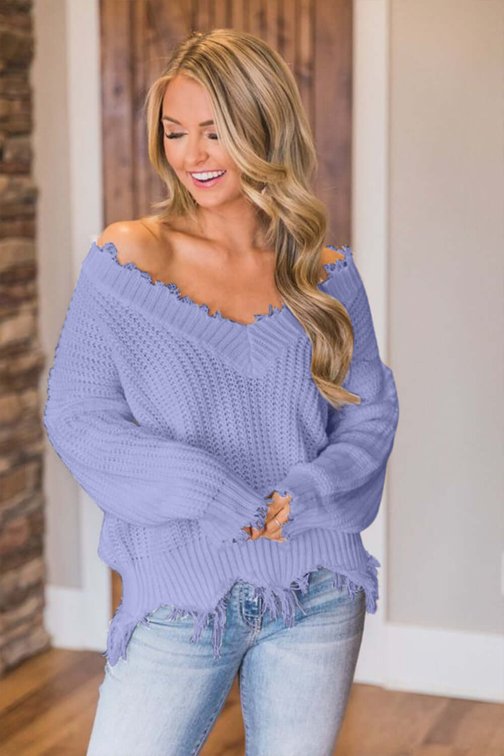 Woman wearing Bella Road frayed hem dropped shoulder sweater in lavender, styled with casual jeans.