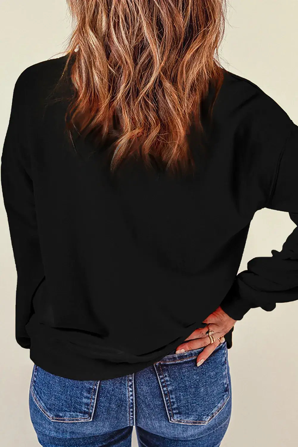 Woman wearing Bella Road SPOOKY Round Neck Long Sleeve Sweatshirt, showcasing back style with cozy fit and trendy look.