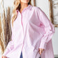 Woman wearing First Love Full Size Striped Button Down High-Low Hem Shirt in pink and white stripes paired with blue jeans.