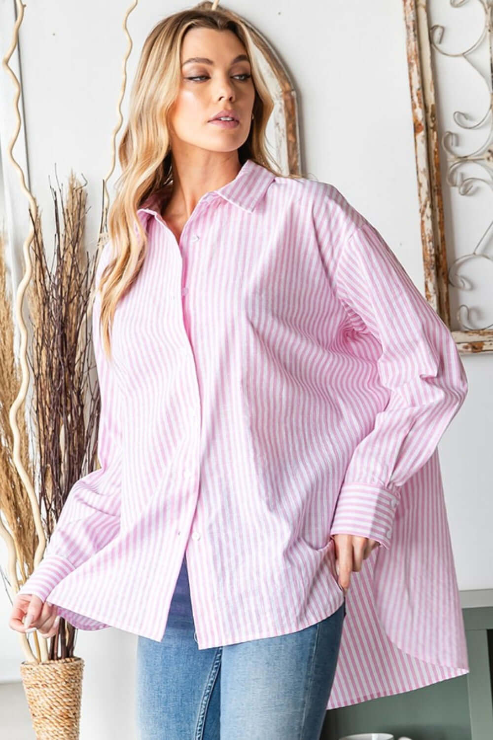 Woman wearing First Love Full Size Striped Button Down High-Low Hem Shirt in pink and white stripes paired with blue jeans.