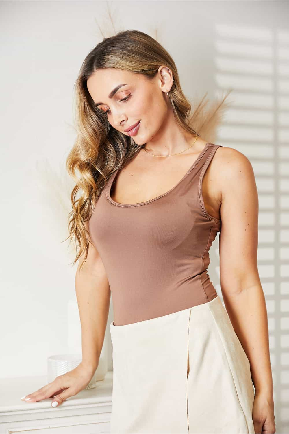 Woman wearing Everyday Full Size Basic Tank Bodysuit in brown, styled with a light skirt, showcasing a sleek and comfortable fit.