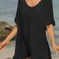 Woman wearing black tied ruffled half sleeve cover-up on the beach, sheer and comfortable cotton-polyester blend, perfect for layering.