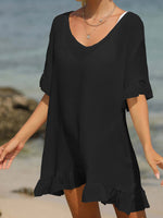 Woman wearing black tied ruffled half sleeve cover-up on the beach, sheer and comfortable cotton-polyester blend, perfect for layering.