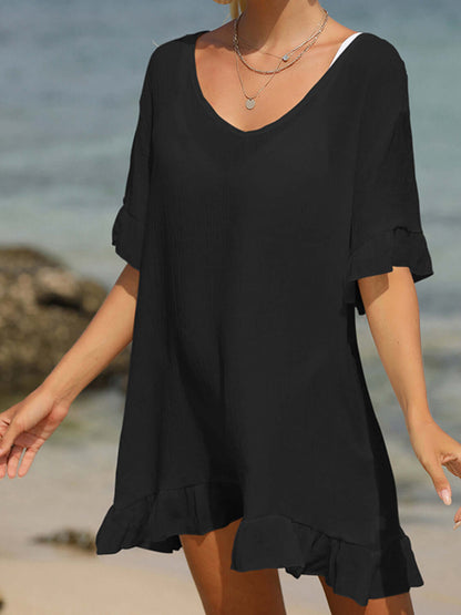 Woman wearing black tied ruffled half sleeve cover-up on the beach, sheer and comfortable cotton-polyester blend, perfect for layering.