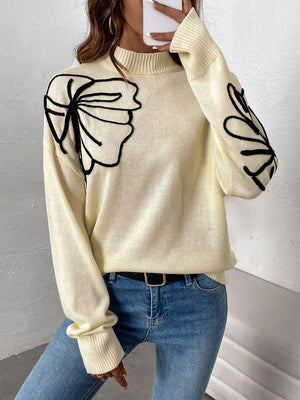 Woman wearing Perfee Mock Neck Dropped Shoulder Long Sleeve Sweater with black floral design and jeans