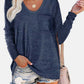 Woman wearing Bella Road round neck long sleeve t-shirt in navy blue with front pocket, paired with ripped denim shorts and beige handbag.