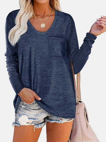 Woman wearing Bella Road round neck long sleeve t-shirt in navy blue with front pocket, paired with ripped denim shorts and beige handbag.