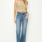 Woman wearing mid-rise frayed hem bootcut jeans by Risen Jeans, styled with a beige crop top and sandals for a chic look