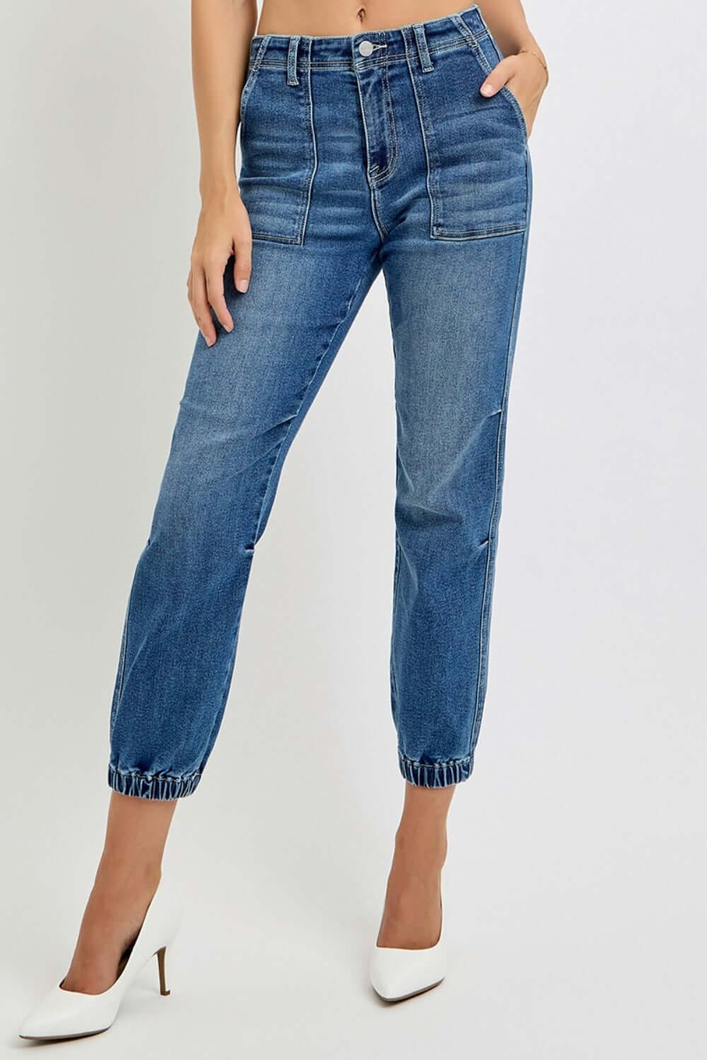 Stylish high-rise ankle jogger jeans with elastic cuffs and a sleek silhouette, paired with white heels for a chic look.