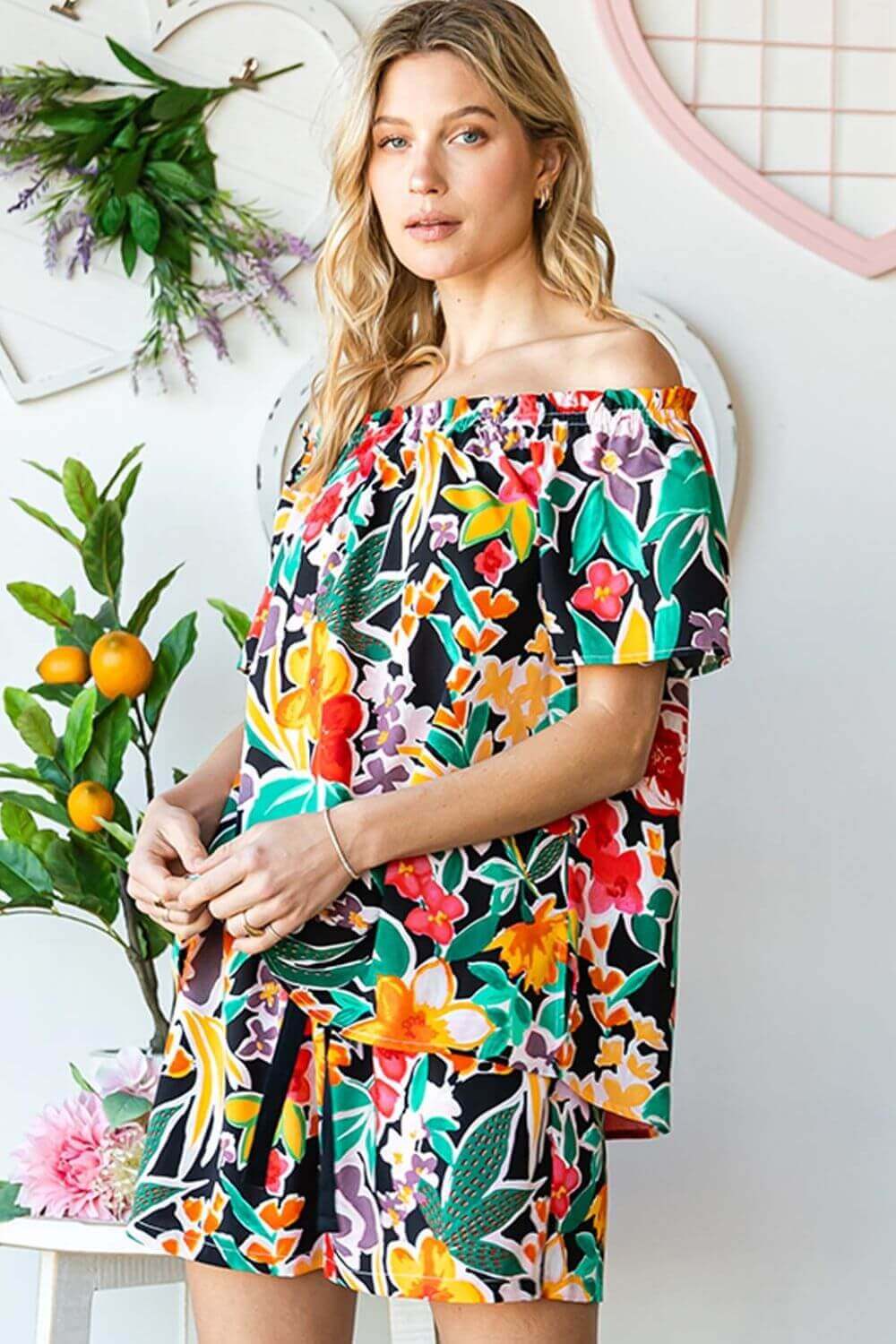 Woman wearing a stylish floral off-shoulder top with vibrant colors and an off-shoulder neckline, perfect for summer outings.