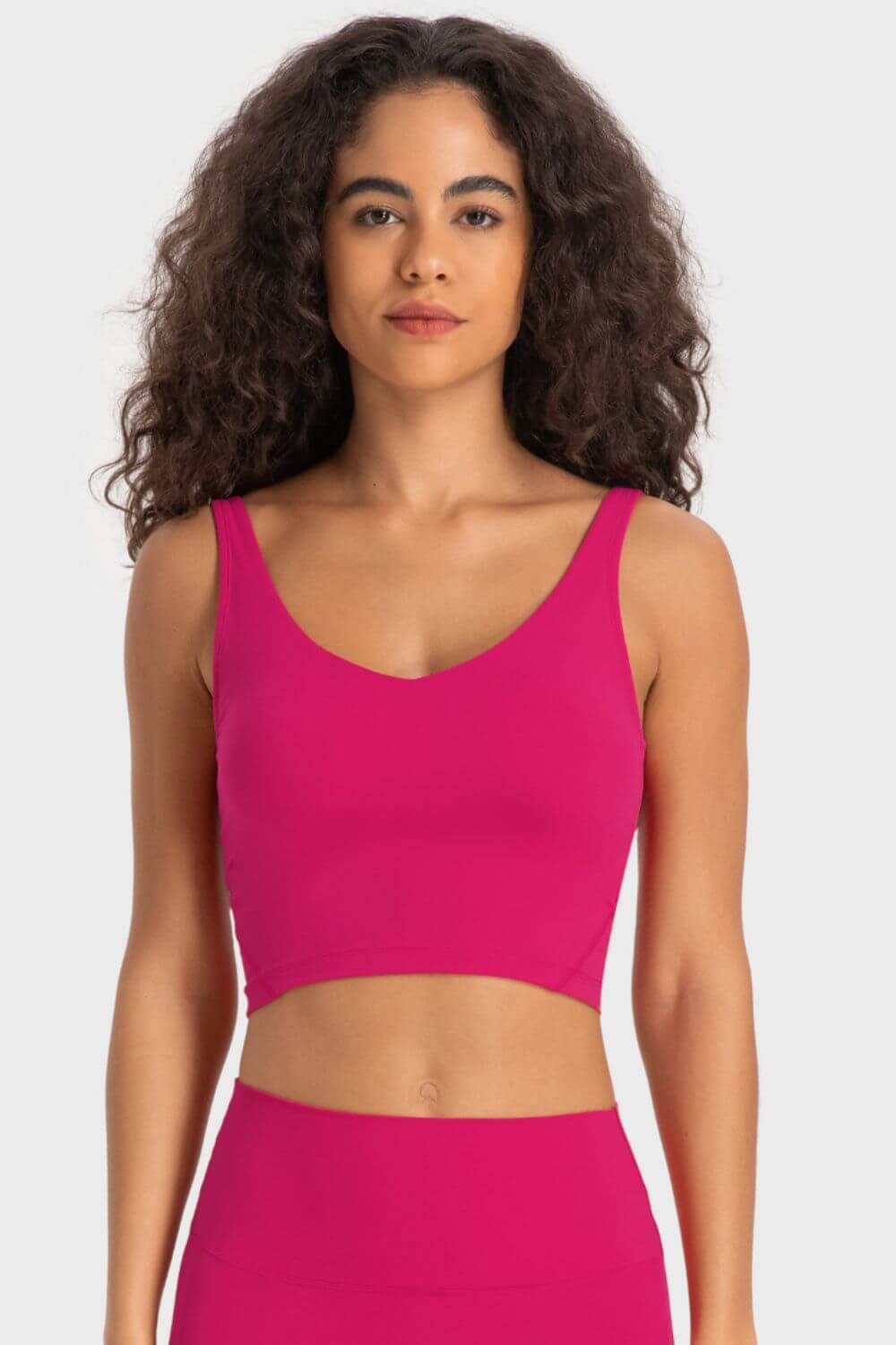 Millennia Deep V-Neck Crop Sports Bra in vibrant pink, showcasing a flattering fit and sporty style. Perfect for workouts!