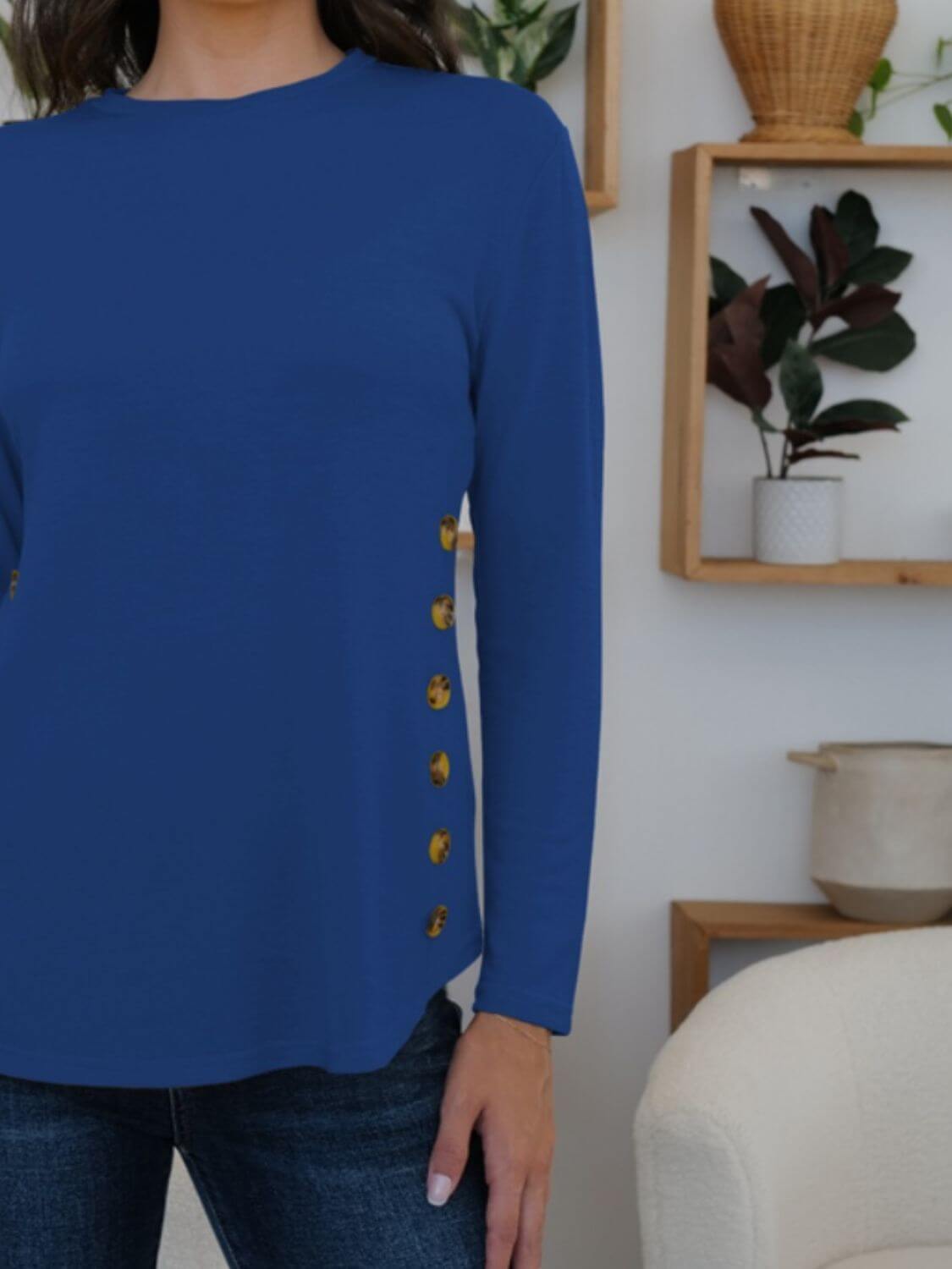 Woman wearing a blue FAM-FAM round neck long sleeve t-shirt with decorative buttons, perfect for casual style and comfort.