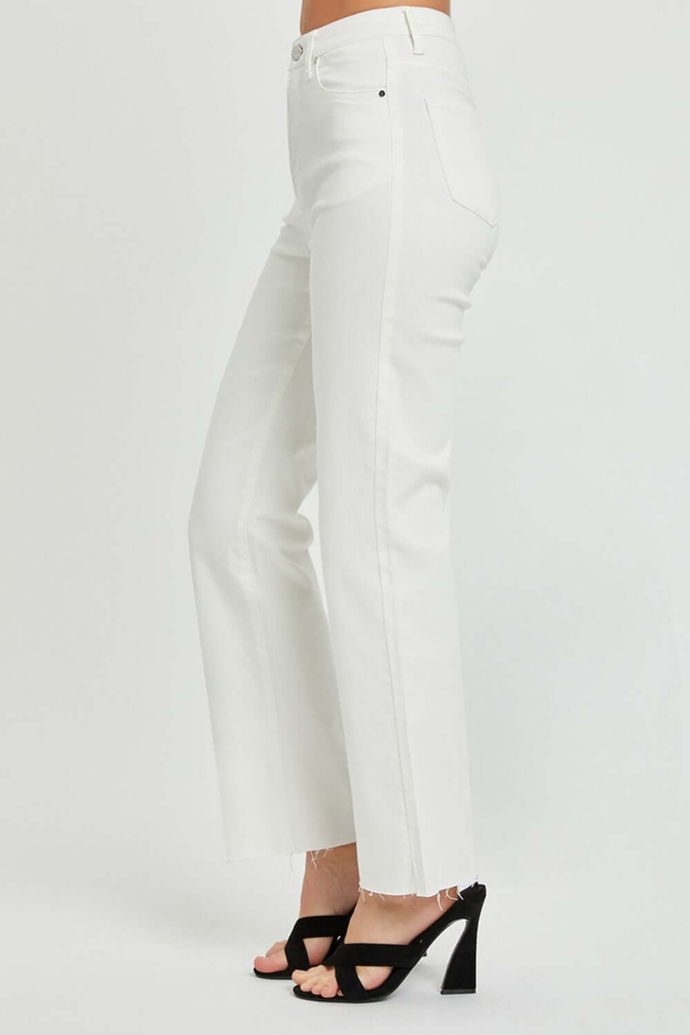 High Rise Tummy Control Straight Risen Jeans in white with raw hem, providing a flattering fit and edgy charm, modeled with black heels