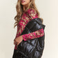 Stylish woman wearing a black shiny metallic puffer vest over a red lace top and black sequin skirt.