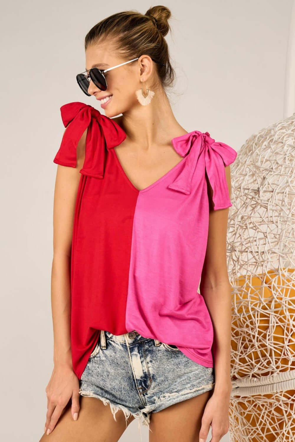 Woman wearing Shoulder Ribbon Tied Contrast Tank with red and pink panels, sunglasses, denim shorts, and earrings