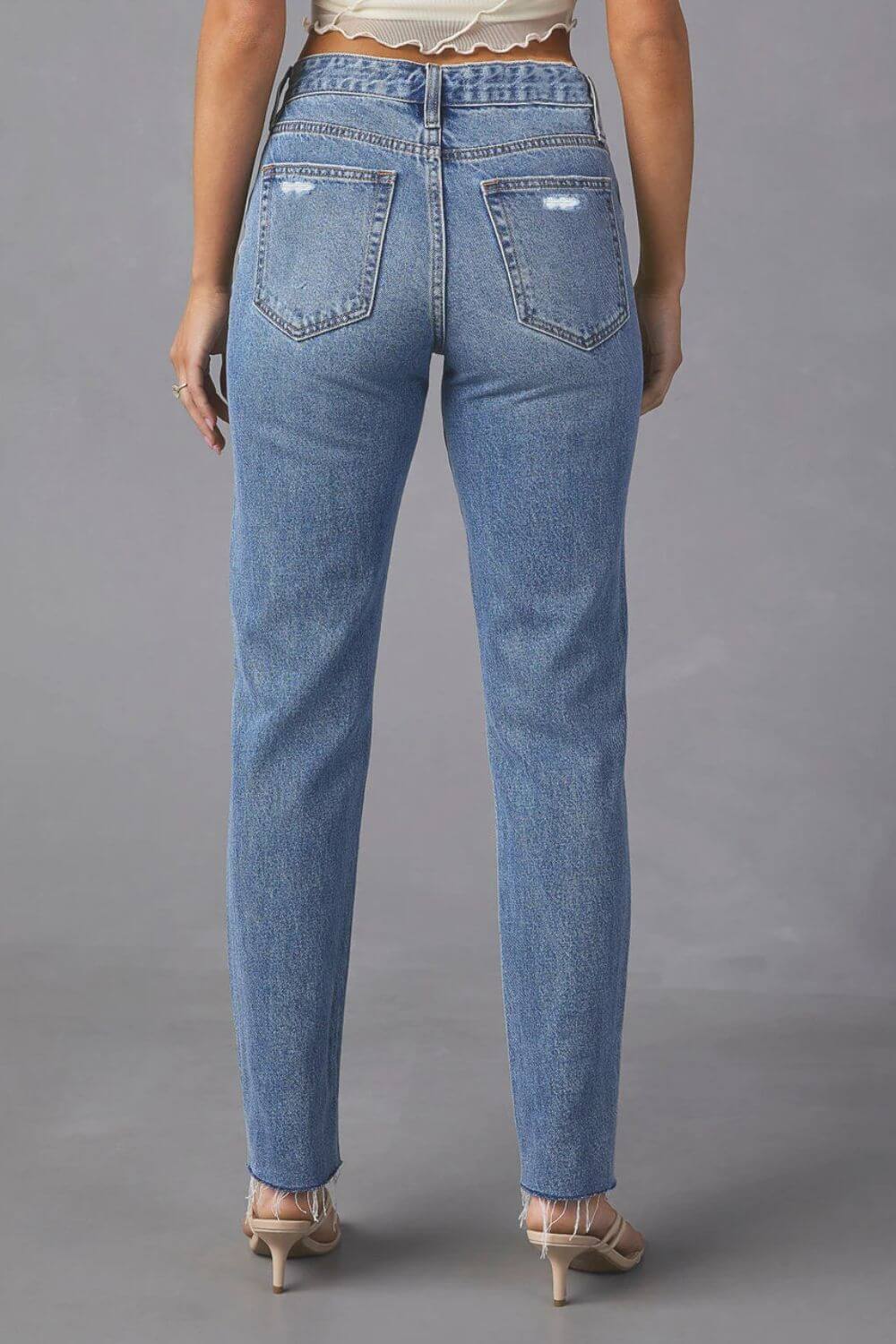 Back view of Distressed Raw Hem Straight Jeans with Pockets in blue denim worn by a model