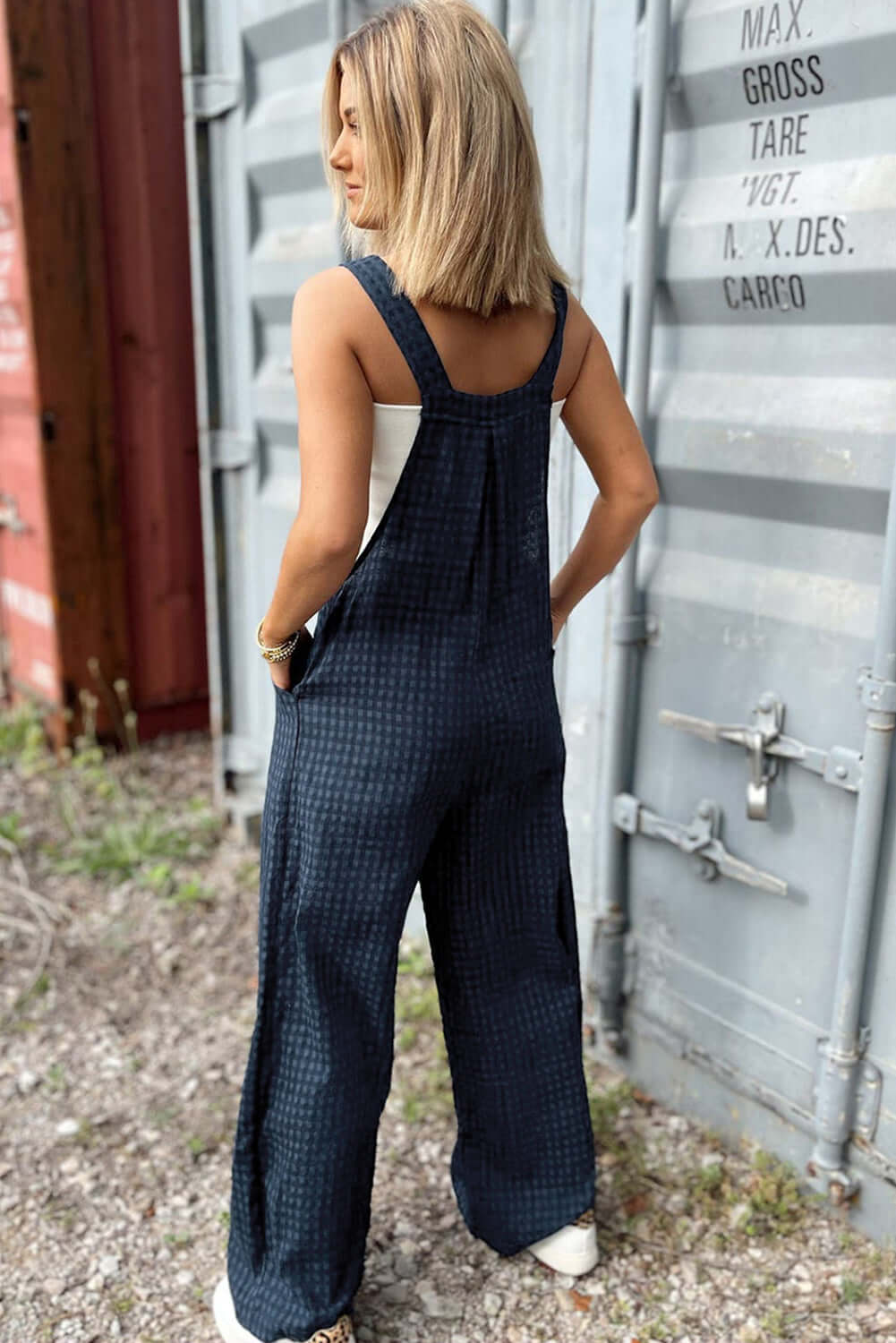 Woman wearing Bella Road plaid wide-leg overalls outdoors, showcasing trendy style with comfortable wide straps and legs.