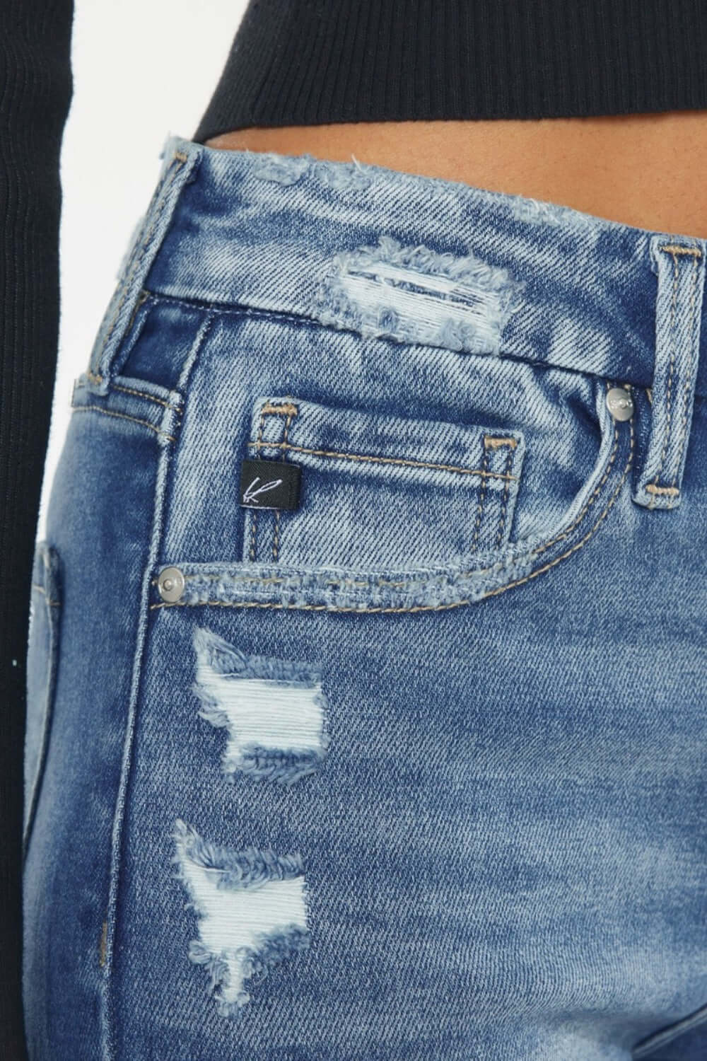 Close-up of Kancan high-rise slim straight jeans with distressed details and wide waistband, showcasing trendy medium stone wash denim.