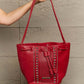 Nicole Lee USA red Amy Studded Bucket Bag with pebbled vegan leather, studded detail, and secure drawstring closure held by a hand.